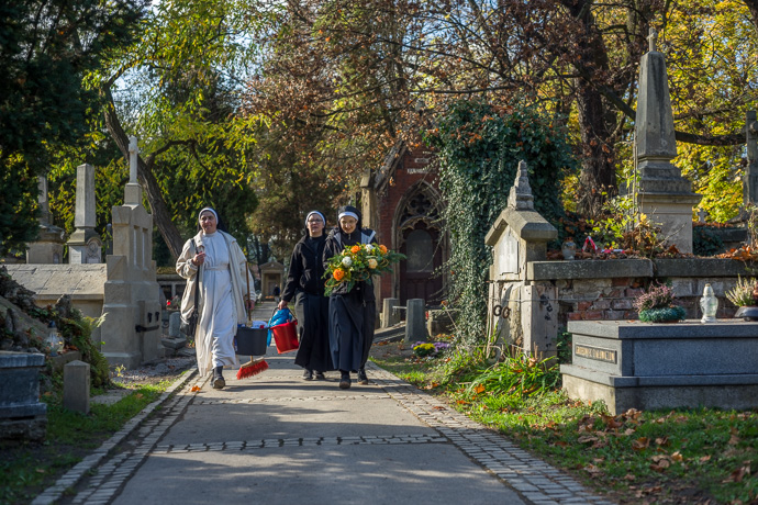 All Saints' Day at Rakowicki Cemetery in Kraków, Poland 2019. Three nuns armed with cleaning equipment and flowers walk across the cemetery, All Saints' Day in Poland. Image: Michel Meijer