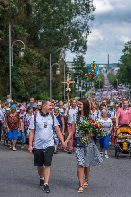 Celebration of Maria ascension in Jasna Góra, Poland 2018. couple walks hand in hand in front of a group of pilgrims. Image: Michel Meijer