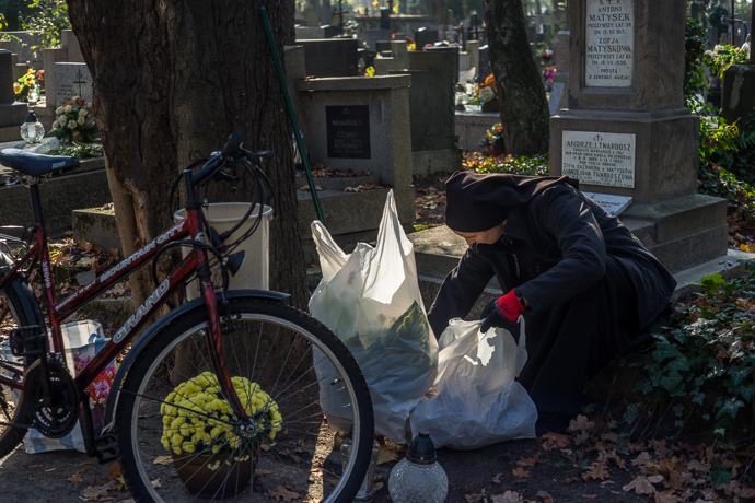 All Saints' Day at Rakowicki Cemetery in Kraków, Poland 2019. A nun cleans a grave and sets flowers on it, All Saints' Day in Poland. Image: Michel Meijer