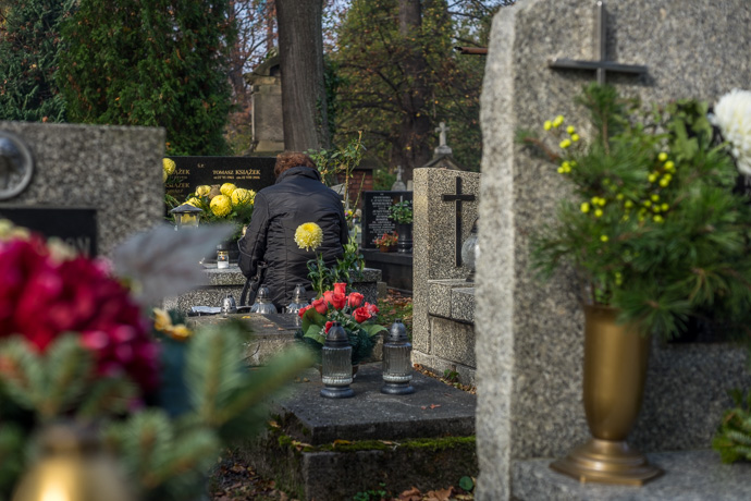 All Saints' Day at Rakowicki Cemetery in Kraków, Poland 2019. A woman kneels before a grave in a cemetery, All Saints' Day in Poland. Image: Michel Meijer
