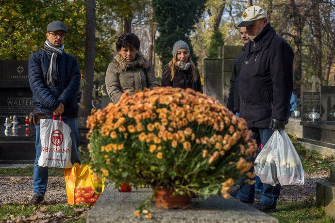 All Saints' Day at Rakowicki Cemetery in Kraków, Poland 2019. Relatives are standing around a grave with flowers and candles, All Saints' Day in Poland. Image: Michel Meijer