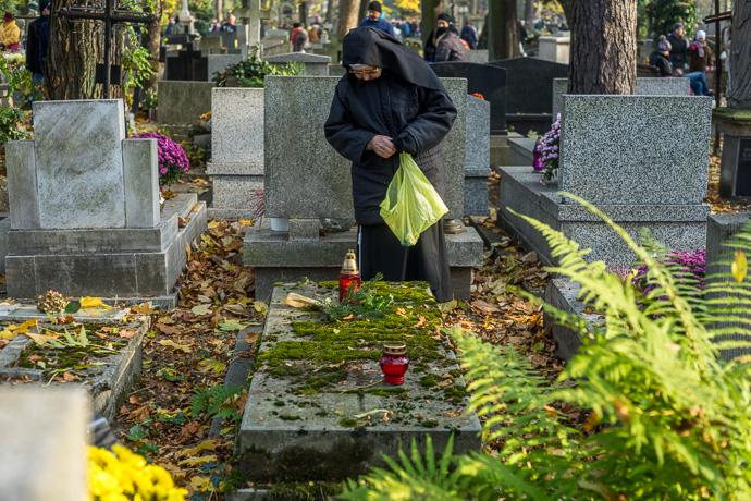 All Saints' Day at Rakowicki Cemetery in Kraków, Poland 2019. A nun stands praying in front of a tombstone in the cemetery, All Saints' Day in Poland. Image: Michel Meijer