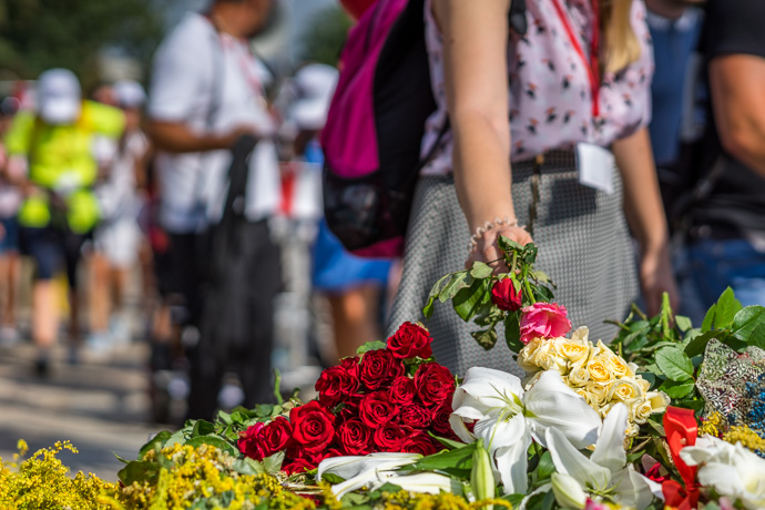 Celebration of Maria ascension in Jasna Góra, Poland 2018. A woman lays flowers on a monument in front of the Jasna Góra pilgrimage site. Image: Michel Meijer