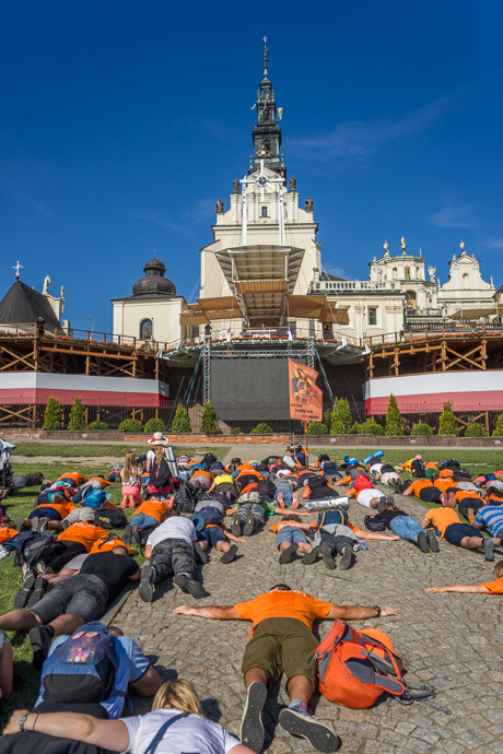 Celebration of Maria ascension in Jasna Góra, Poland 2018. A group of pilgrims lies on the ground in front of the Jasna Góra pilgrimage site. Image: Michel Meijer