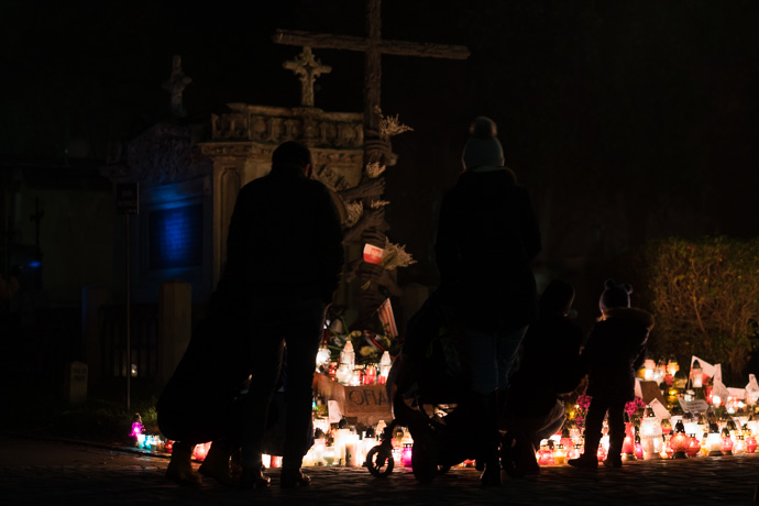 All Saints' Day at Rakowicki Cemetery in Kraków, Poland 2019. A family stands in front of the monument honouring the victims of the communist regime in Poland, All Saints' Day in Poland Image: Michel Meijer