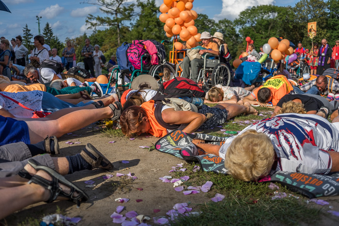 Celebration of Maria ascension in Jasna Góra, Poland 2018. A group of pilgrims lie on the ground and pray in front of the Jasna Góra pilgrimage site. Image: Michel Meijer