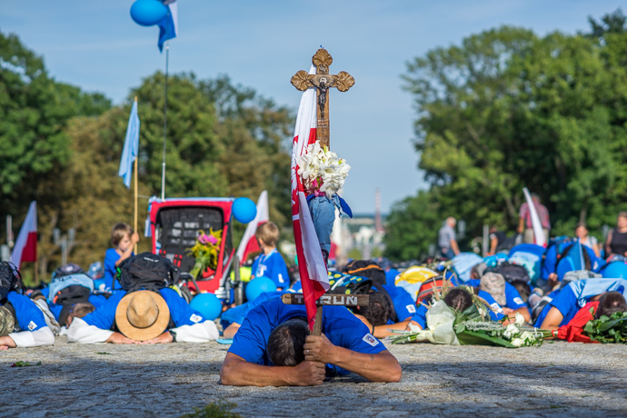 Celebration of Maria ascension in Jasna Góra, Poland 2018. A group of pilgrims lie on the ground and pray in front of the Jasna Góra pilgrimage site. Image: Michel Meijer