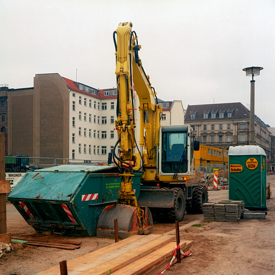 A waste container, a yellow excavator and a mobile toilet on a building site. Image: Michel Meijer