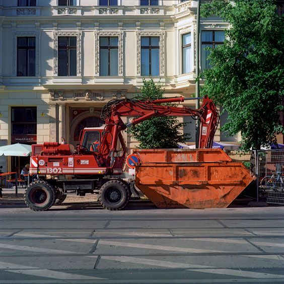 A red excavator and waste containers on a street in Berlin. Image: Michel Meijer