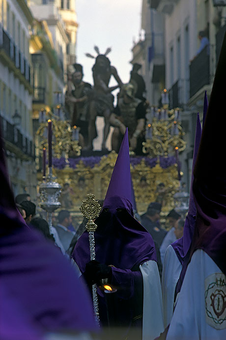 Hooded penitents walk in procession through the street. One of the altars can be seen in the background. Image: Michel Meijer