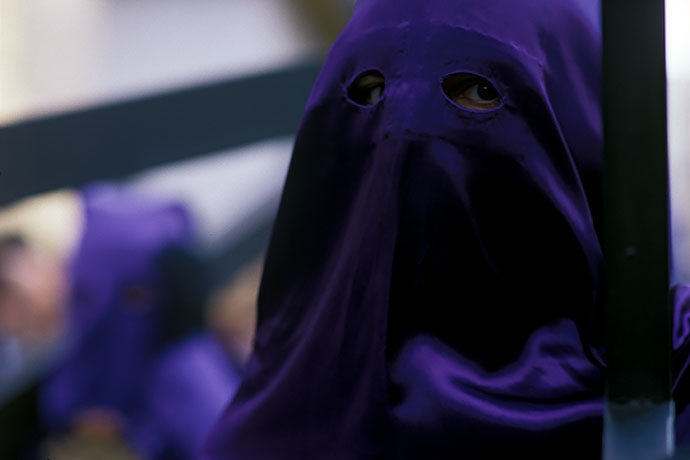 Hooded men walk in the procession, each carrying a wooden cross on their shoulder. Image: Michel Meijer