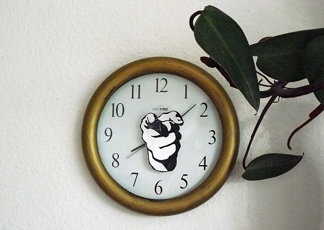 Eine Wanduhr mit dem Bild eines zeigenden Hands.  Eine Arbeit von Marcel Schock.